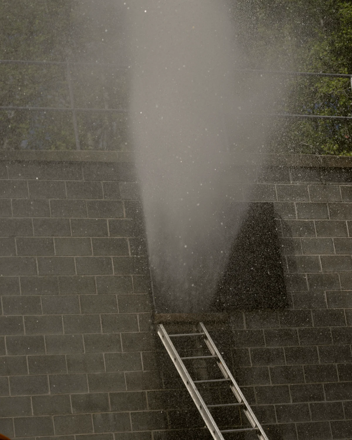 Colonne de brume d'une laveuse à pression contre un mur de blocs : photo d'illustration